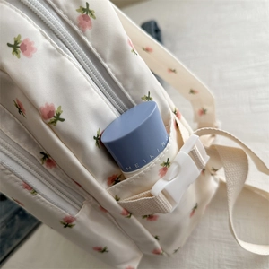 Close-up of floral print backpack showing side pocket with cosmetic item and plastic buckle