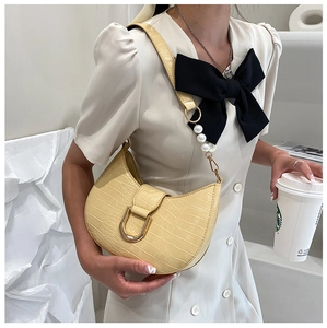 Dettaglio borsa hobo crema con texture coccodrillo, fibbia dorata e accenti di perle