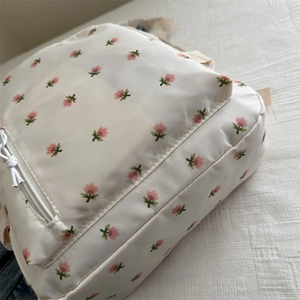 Close-up of lightweight nylon backpack featuring pink floral patterns and white zippers