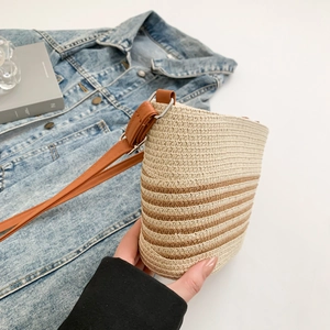 Detailed close-up of woven bucket bag with striped pattern and adjustable brown shoulder strap