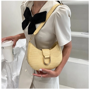 Dettaglio borsa a mezzaluna beige effetto coccodrillo con fibbia dorata su modella