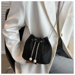 Detail van zwarte emmer-tas met strassteentjes, zilveren ketting en parelkwastje