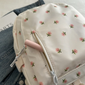 Close-up of floral school backpack with dual zippers and cream pink flower pattern