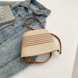 Detail of hand-woven straw bucket bag with dark brown stripes and adjustable leather strap