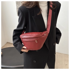 Detail of red woven texture crossbody bag with gold zipper on black suit blazer