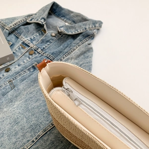 Detailed close-up of stripe woven bag featuring a metal zipper and smooth leather lining
