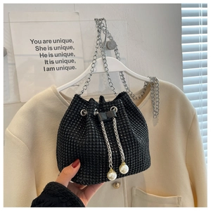 Detail van zwarte strass emmertas met zilveren ketting en witte parel trekkoorden