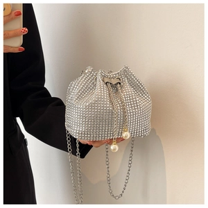 Detail van zilveren bucketbag met strass steentjes, parelkoord en een metalen ketting
