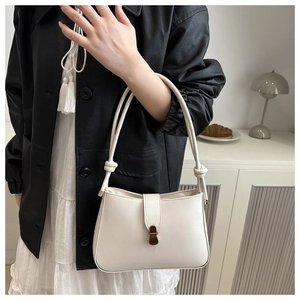 Detail of a creamy white leather handbag with unique knotted strap and vintage metal lock