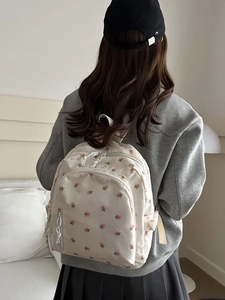 Mori style off-white floral backpack with multiple pockets shown on model in soft light