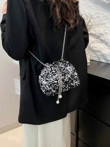 Detail of silver sequin bucket bag featuring metallic chain strap and pearl drawstring closure