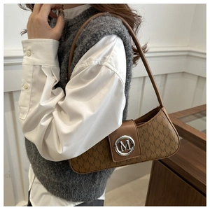 Close-up of vintage brown baguette bag with leather strap and metallic M logo buckle