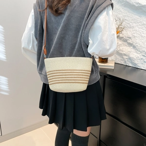Minimalist straw woven crossbody bag with brown stripes and long leather strap for summer