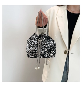 Close-up of sparkling sequin bucket bag with metal chain and pearl drawstring detail