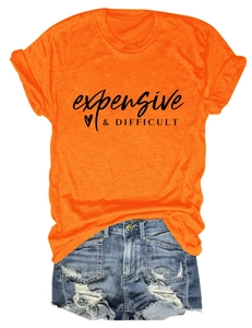 Flat lay of an orange crewneck t-shirt with expensive & difficult text and ripped denim shorts