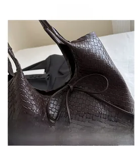 Detail of hand-woven dark brown tote bag featuring a leather bow and premium texture