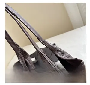 Macro shot of dark brown woven leather texture and premium stitching on a tote bag