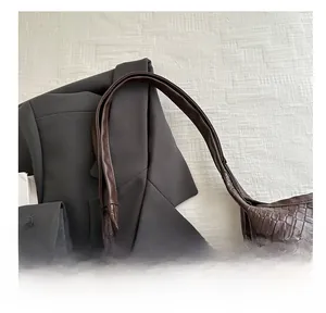 Detail showing the comfortable rounded handle and woven texture of the brown tote bag