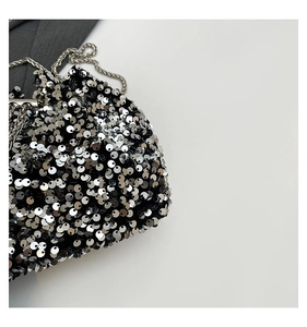 Close-up of shimmering silver sequins on black bucket bag with sleek metal chain