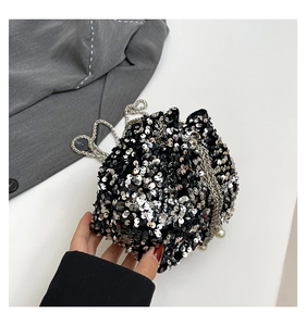 Close-up of silver sequin bucket bag with metal chain strap and white pearl drawstring details
