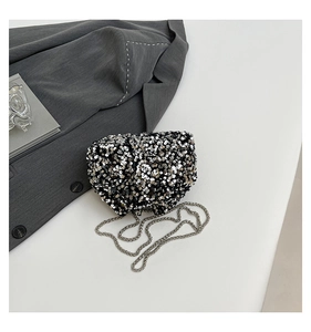 Detailed view of silver sequin evening bag with metallic chain strap on minimalist background