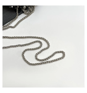 Detailed macro view of the silver braided metal chain strap and black sequin bag details