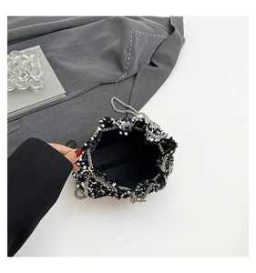 Detailed view of silver sequin bucket bag with chain strap on chic grey office background