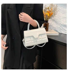 Close-up of white glossy crossbody bag with geometric square embossing and top handle