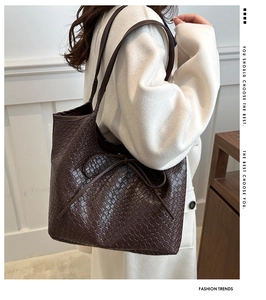 Detail of dark brown woven leather tote bag with drawstring bow on soft coat