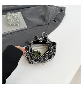 Detail of silver sequin bucket bag showing interior space with phone and makeup items