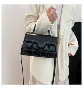 Close-up of black glossy handbag with 3D chocolate embossed texture and wavy flap design
