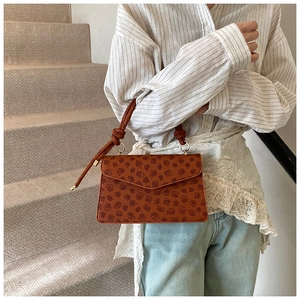 Detailansicht der braunen Handtasche mit Blumenprägung und modischem Knotengriff-Design