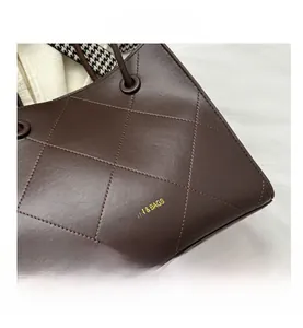 Dettaglio borsa shopper trapuntata marrone scuro con logo e nastro decorativo pied de poule