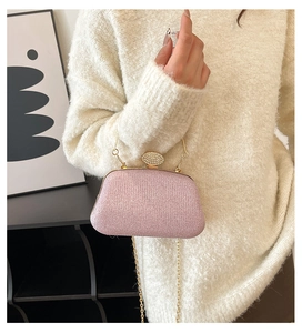 Pochette da sera rosa glitterata con catena dorata e chiusura a diamante su modella