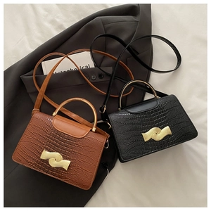 Detail of stone textured leather handbags in black and brown with gold wave buckles
