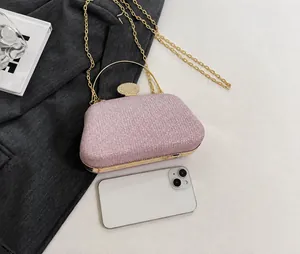 Dettaglio borsa da sera rosa glitterata con manico dorato accanto a uno smartphone di misura