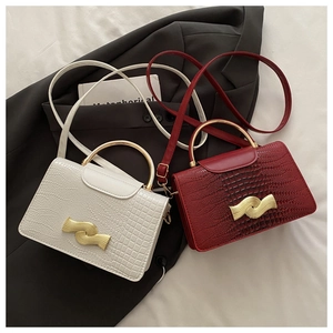 Detail of stone textured flap bags in white and burgundy with wave-shaped metal locks