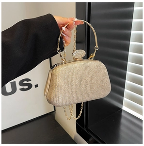 Dettaglio borsa da sera con paillettes dorate, manico in metallo e chiusura strass