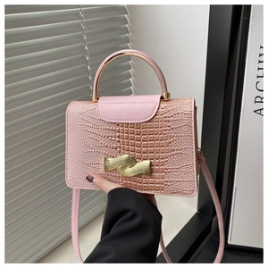 Detail of pink croc-embossed bag with gold wave buckle and metallic top handle