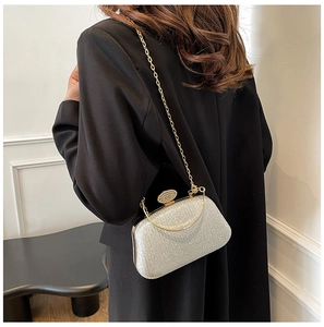 Dettaglio della pochette da sera con glitter argento, catena dorata e fibbia di cristalli