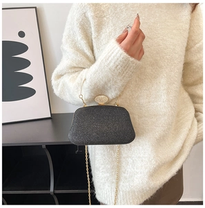 Primo piano dell'elegante pochette da sera nera glitterata con catena d'oro e strass