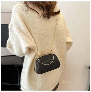 Dettaglio di una borsa da sera nera glitterata con catena dorata e fibbia diamantata