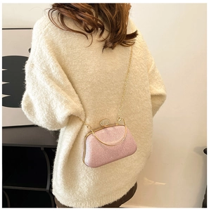 Dettaglio borsa da sera rosa glitterata con catena dorata su un maglione soffice