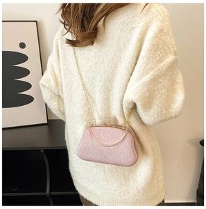 Vista posteriore di una pochette glitter rosa con chiusura strass e catena d'oro su modella