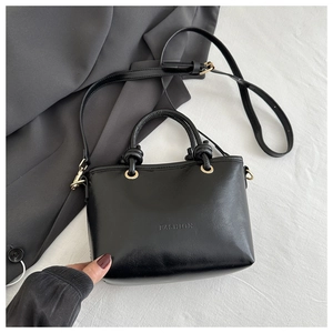 Detail of black glossy bucket bag with FASHION engraving and golden ring hardware