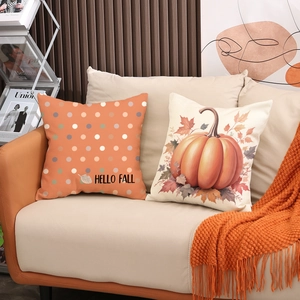 Cuscini decorativi autunnali con zucca e foglie di acero su divano con coperta arancione