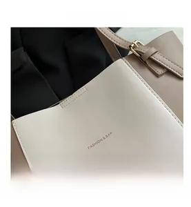 Close-up of contrast stitching and golden metal buckle on ivory and brown leather tote