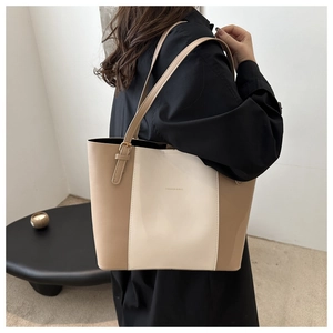 Detail of a large color-block tote bag featuring adjustable straps and printed letters