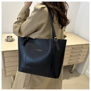 Detail of black leather tote bag with gold FASHION & BAG lettering and metallic hardware