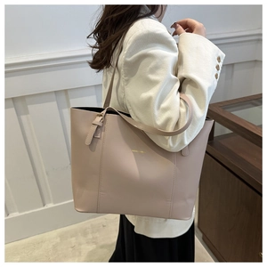 Detail view of large beige leather tote bag featuring gold FASHION & BAG lettering